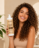 Jeune femme aux cheveux longs bouclés tenant dans sa main le format 1 litre du shampoing soin lavant enrichi en coco